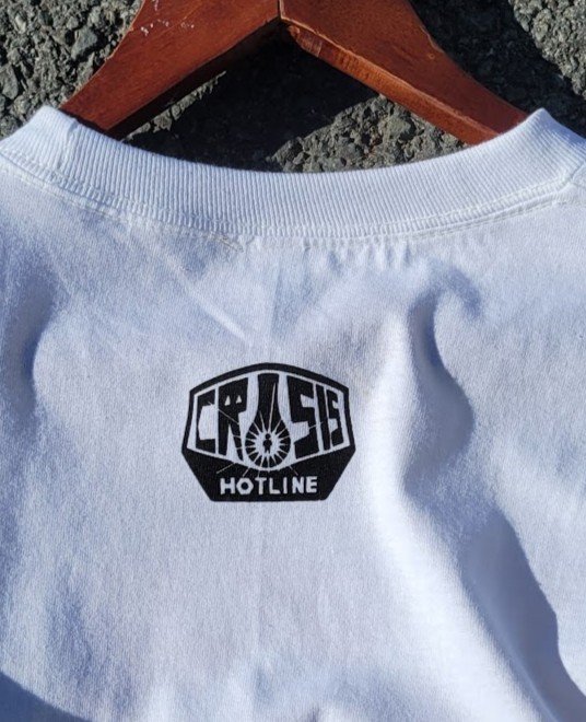 Crisis Hotline merch: white t-shirt with a small black Crash Hotline logo at the back of the neck