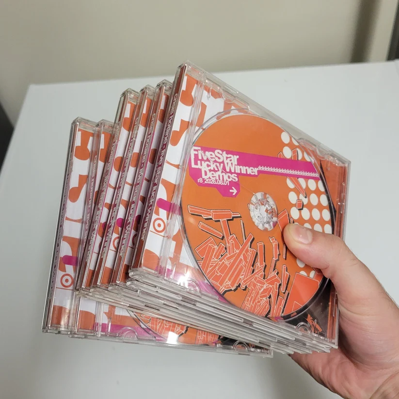 Hand holding a stack of Five Star Lucky Winner CDs by Crisis Hotline in orange-and-pink jewel cases