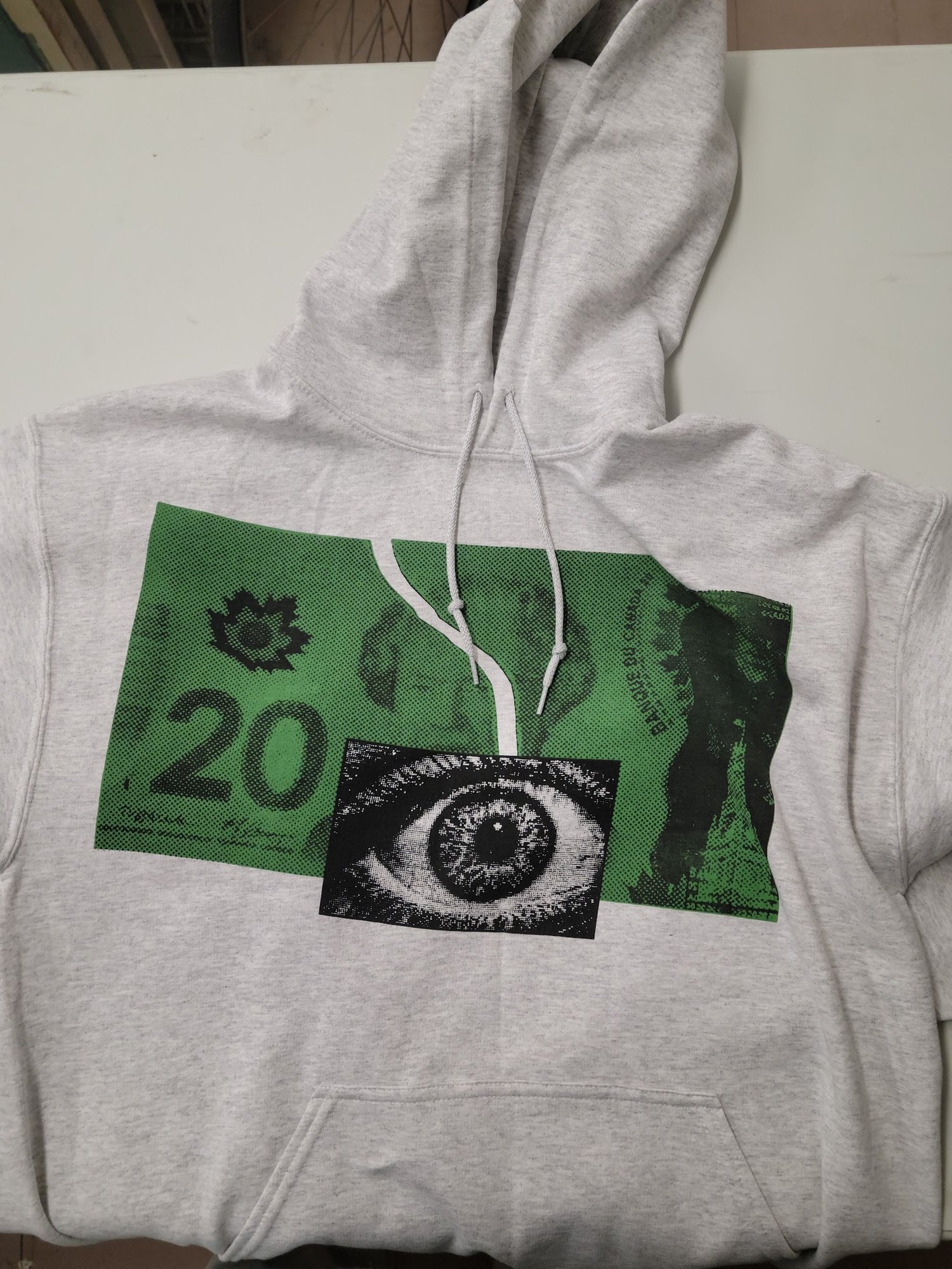 Crisis Hotline merch: gray hoodie with an eye and green banknote graphic