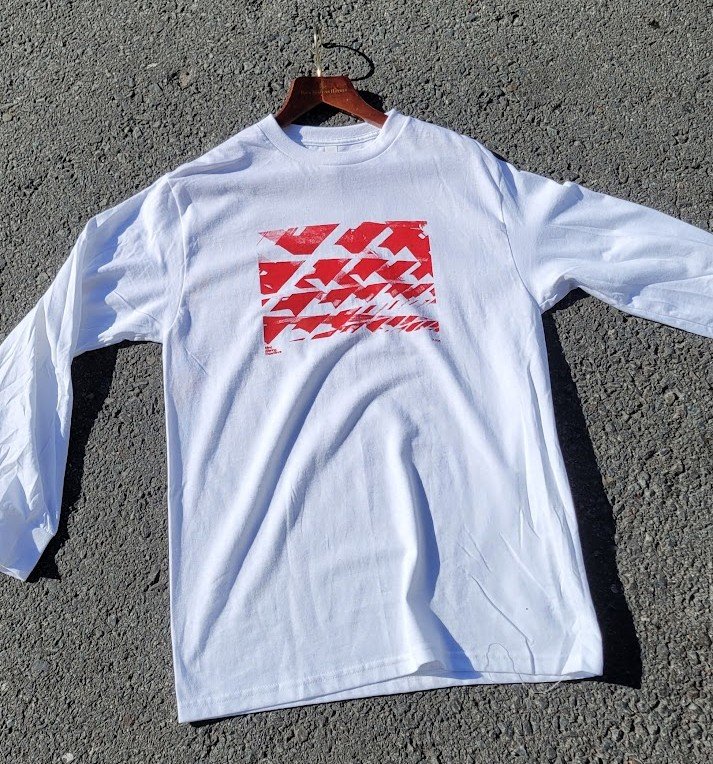 Crisis Hotline merch: white long-sleeve shirt with a red graphic, laid on gravel